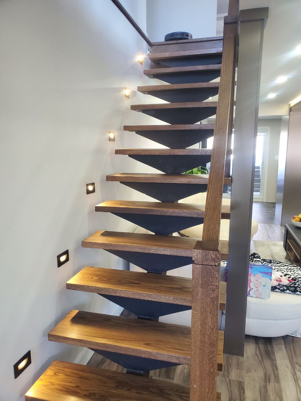 A wooden staircase with a metal railing is in a living room.