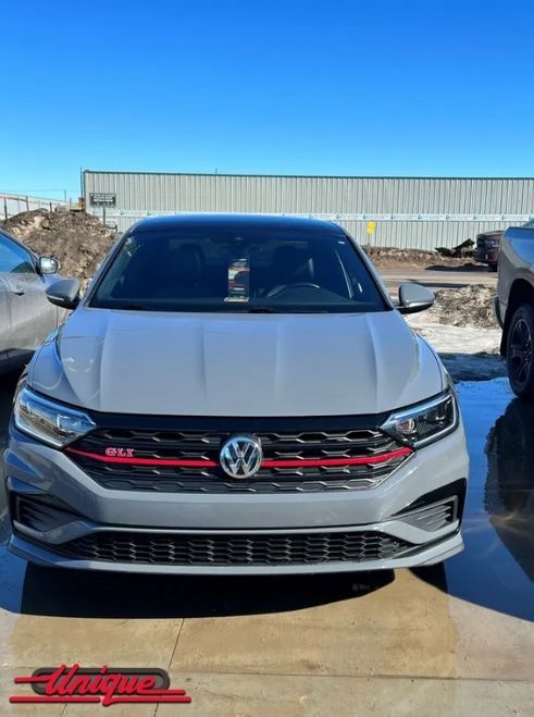 A white volkswagen jetta is parked in a parking lot.