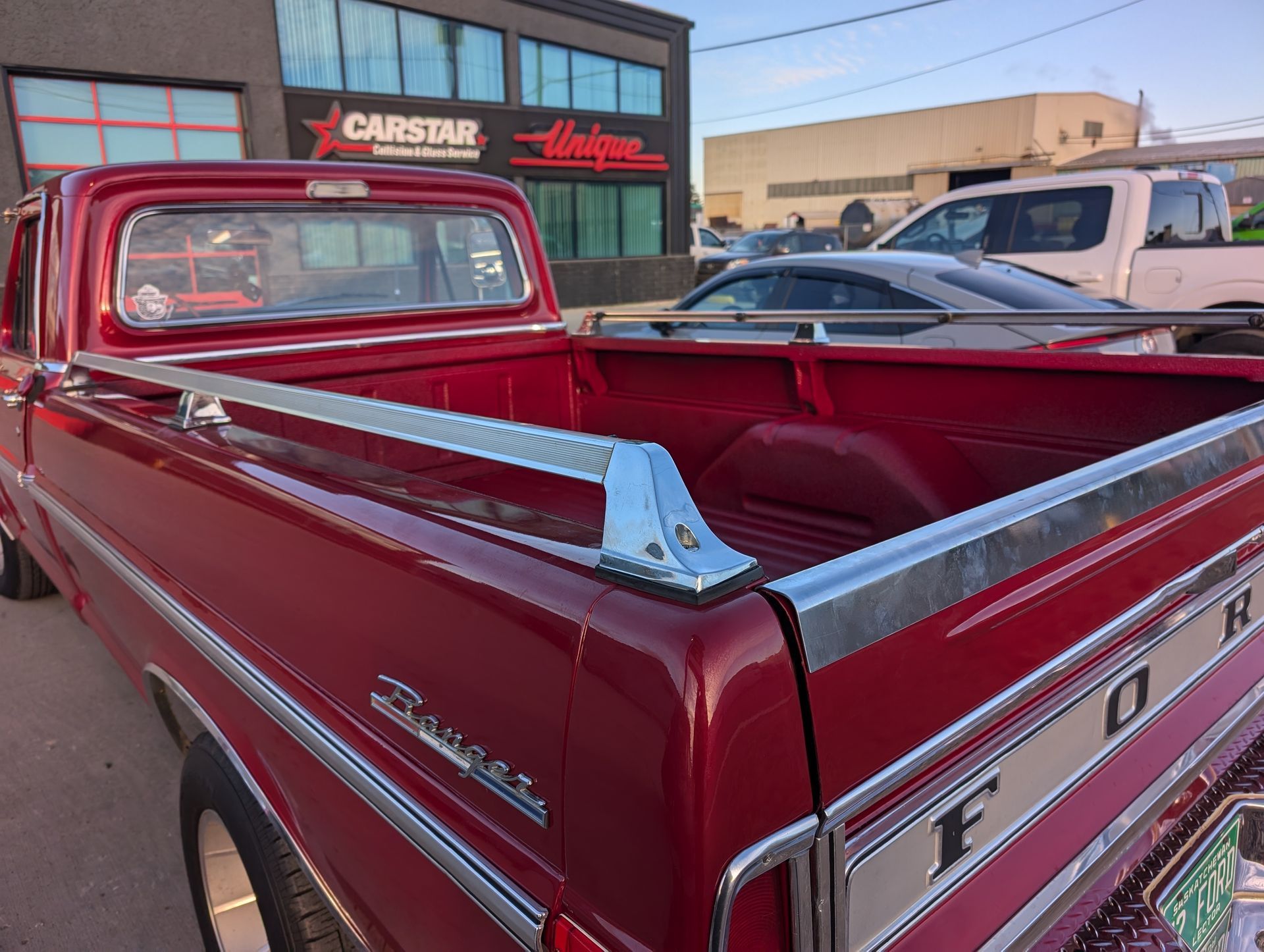 A red ford truck is parked in front of a carstar building.