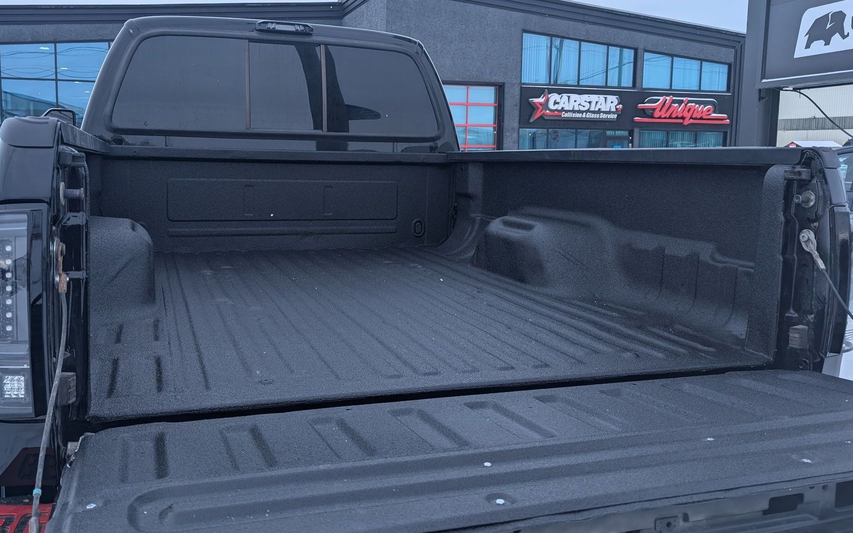 A black truck is parked in the snow in front of a building.
