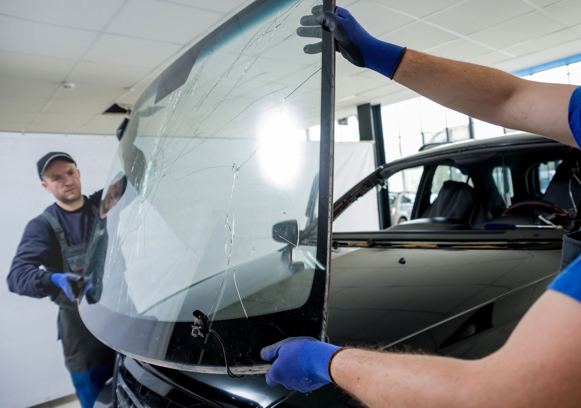 Two men are installing a windshield on a car.