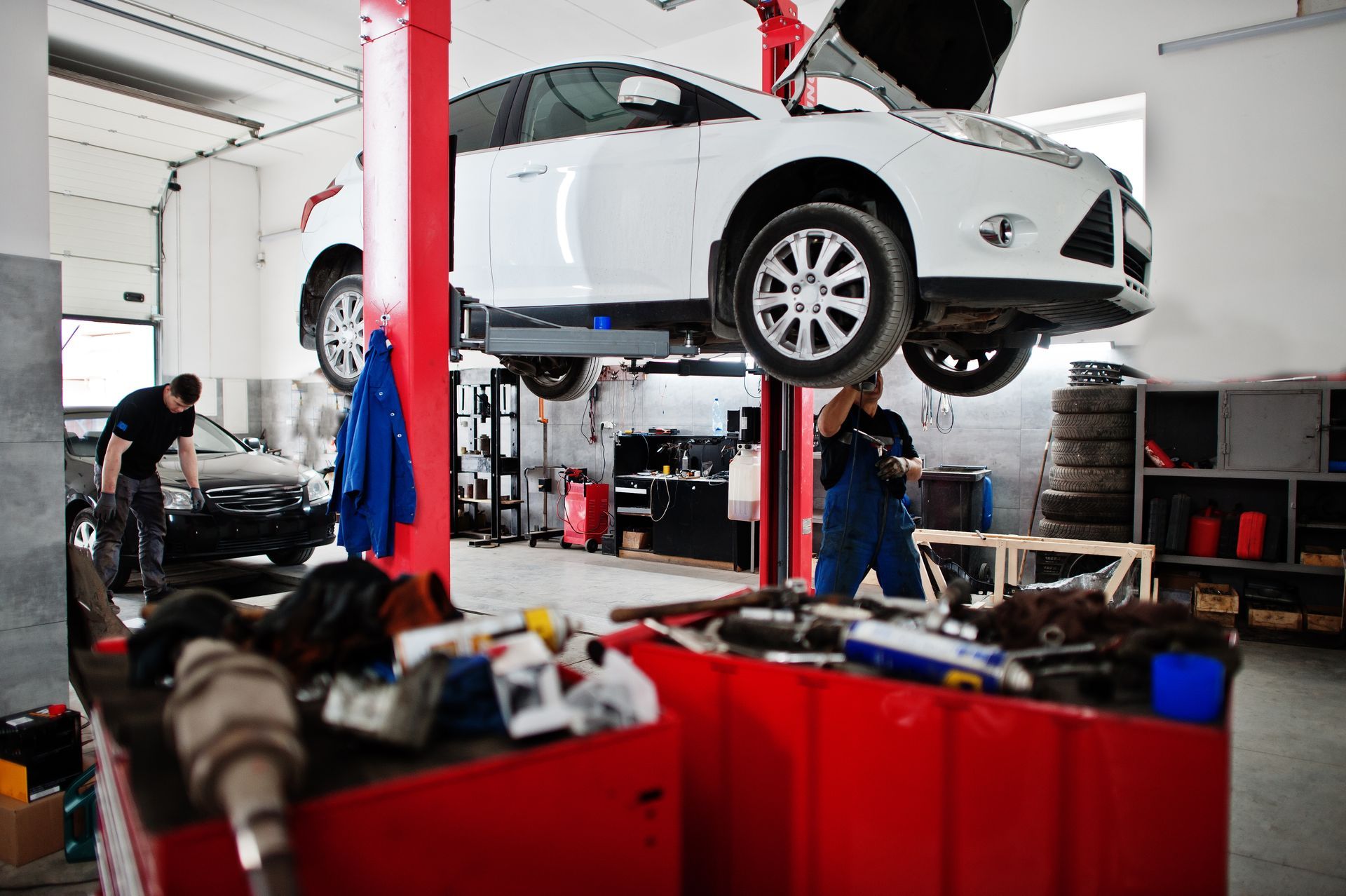 A white car is sitting on a lift in a garage.