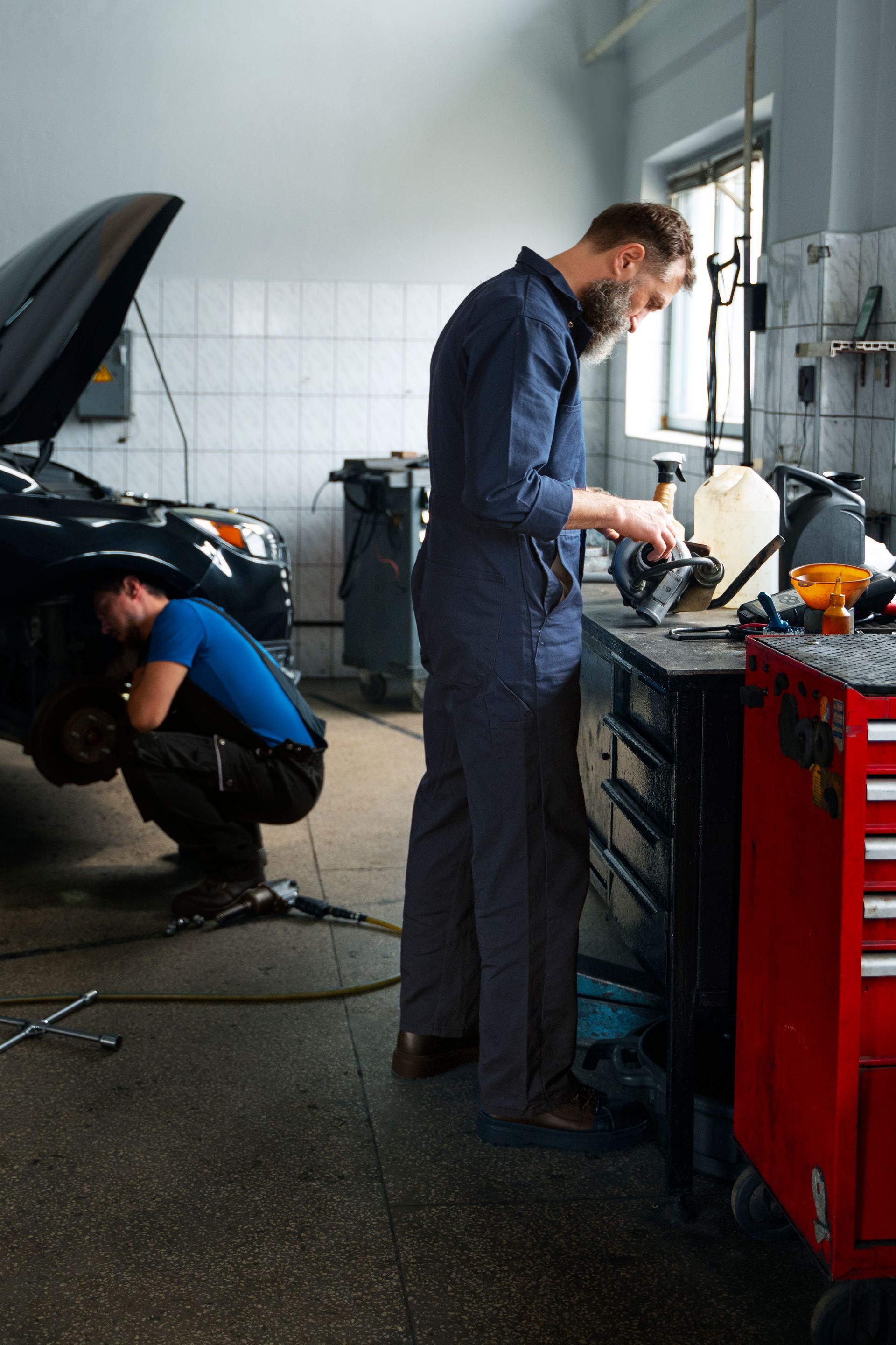 Two mechanics are working on a car in a garage.