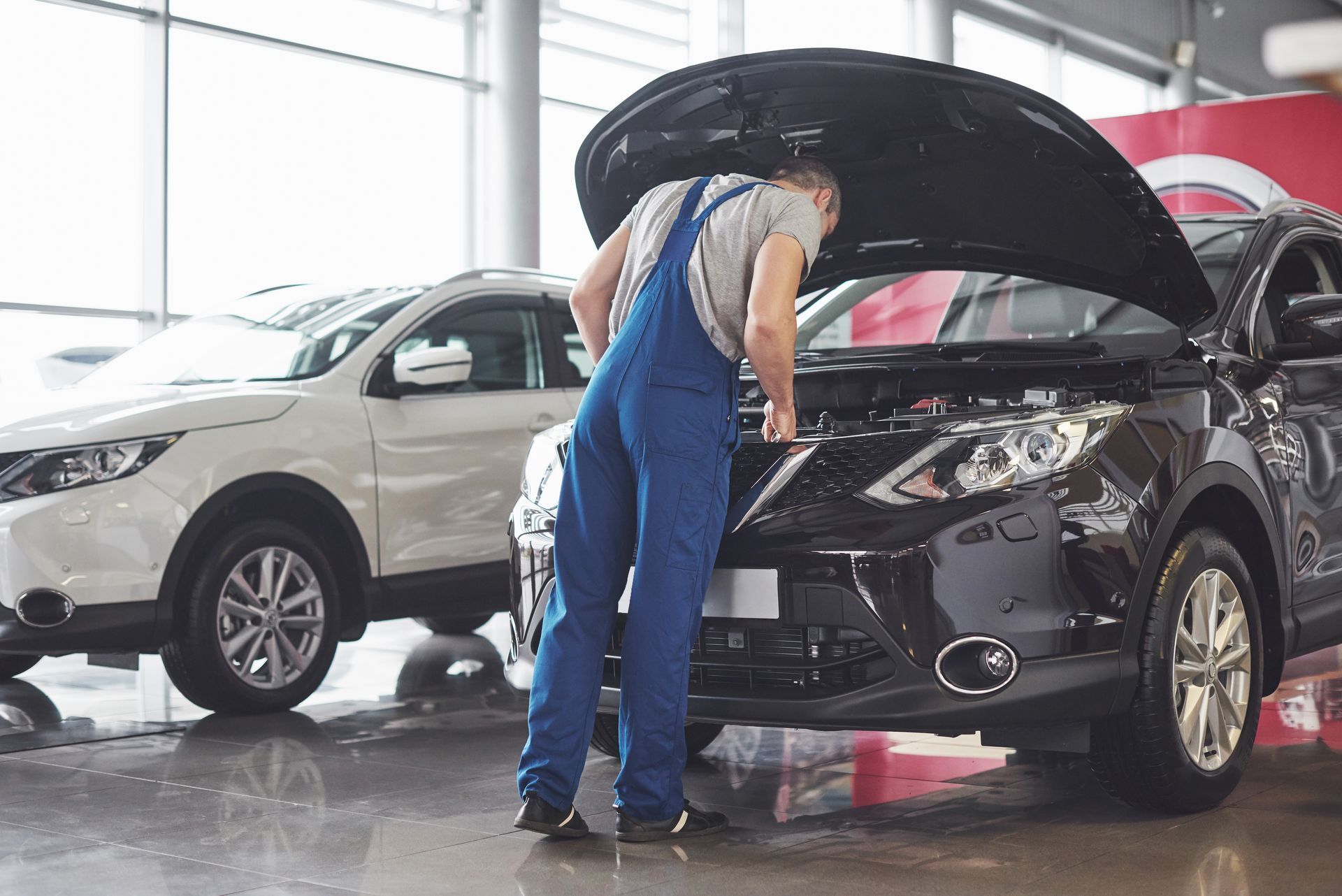 A mechanic is looking under the hood of a car.