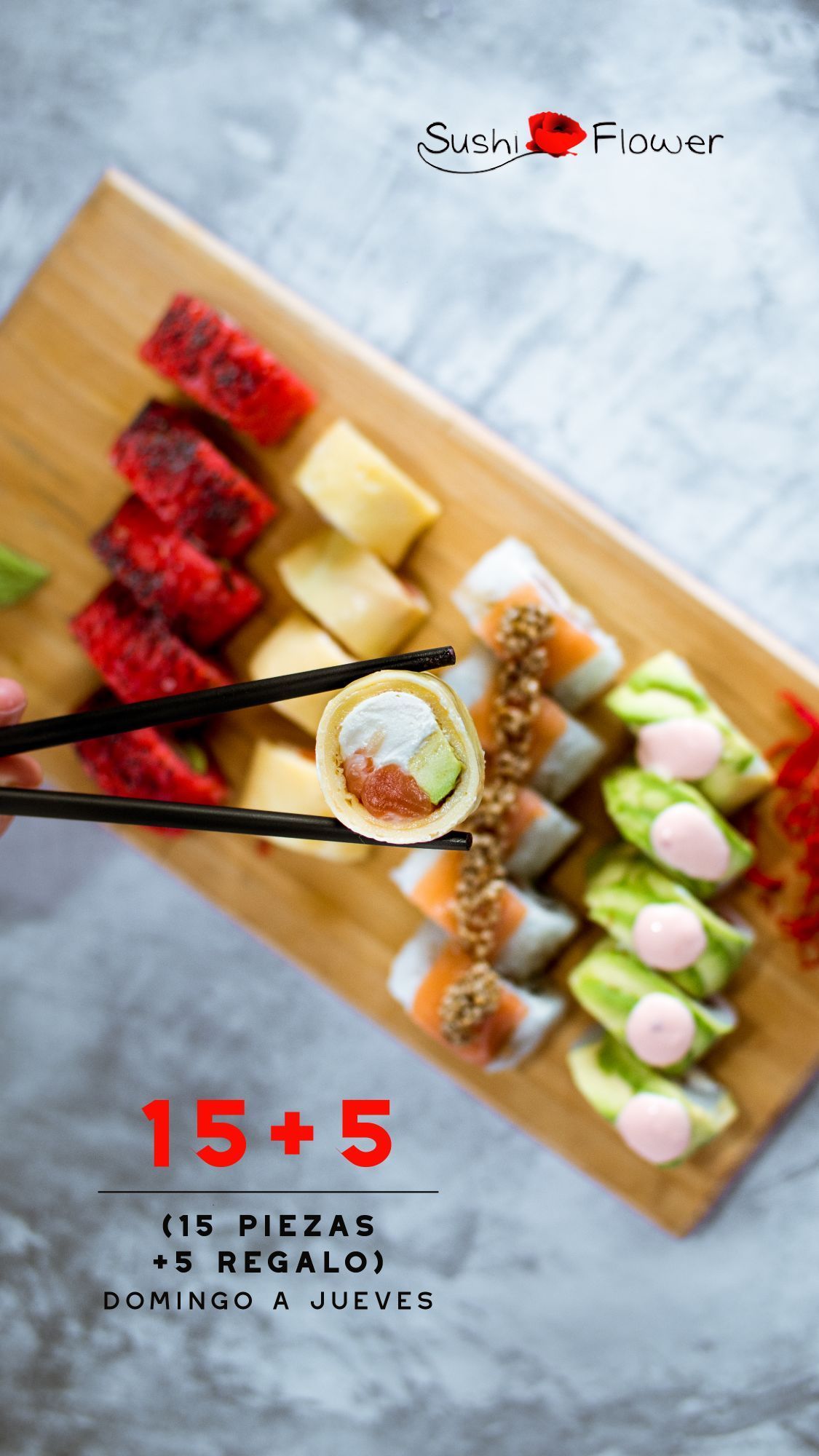 A person is holding a sushi roll with chopsticks.