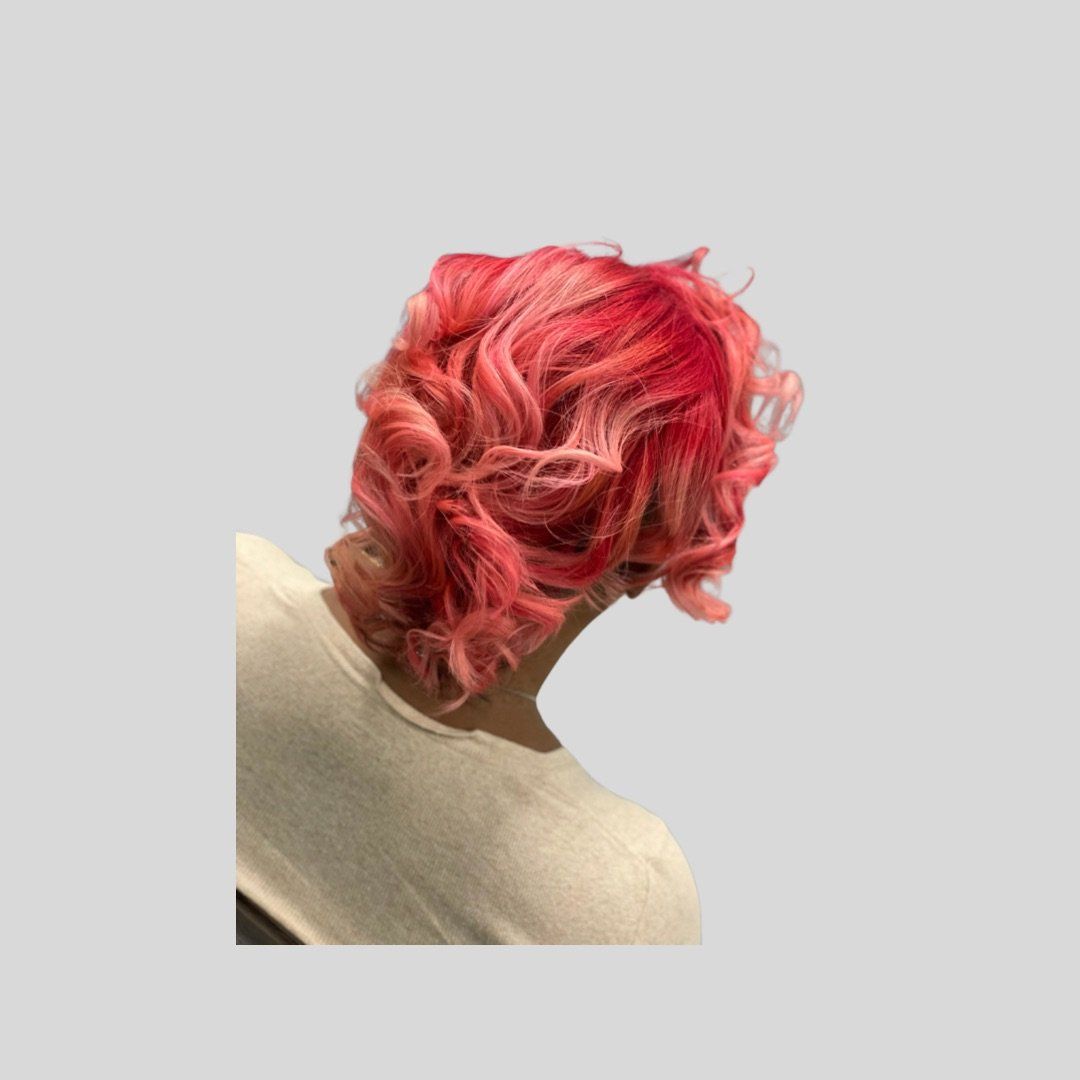 A woman with pink hair is wearing a white shirt.