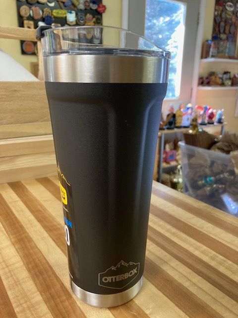 A black tumbler is sitting on a wooden table.