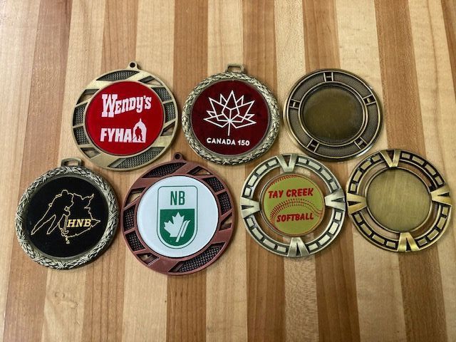 A bunch of medals on a wooden table with one that says wendy 's