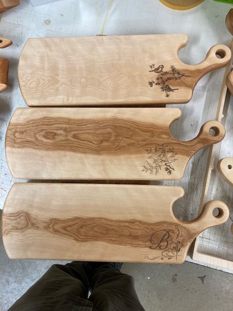 Three wooden cutting boards are sitting on top of each other on a table.