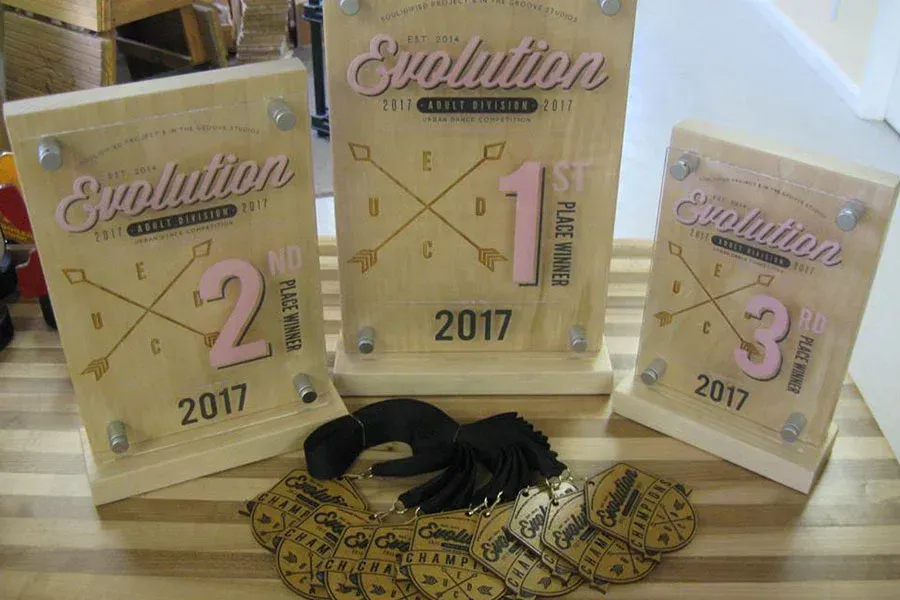 Three wooden trophies are sitting on top of a wooden table.