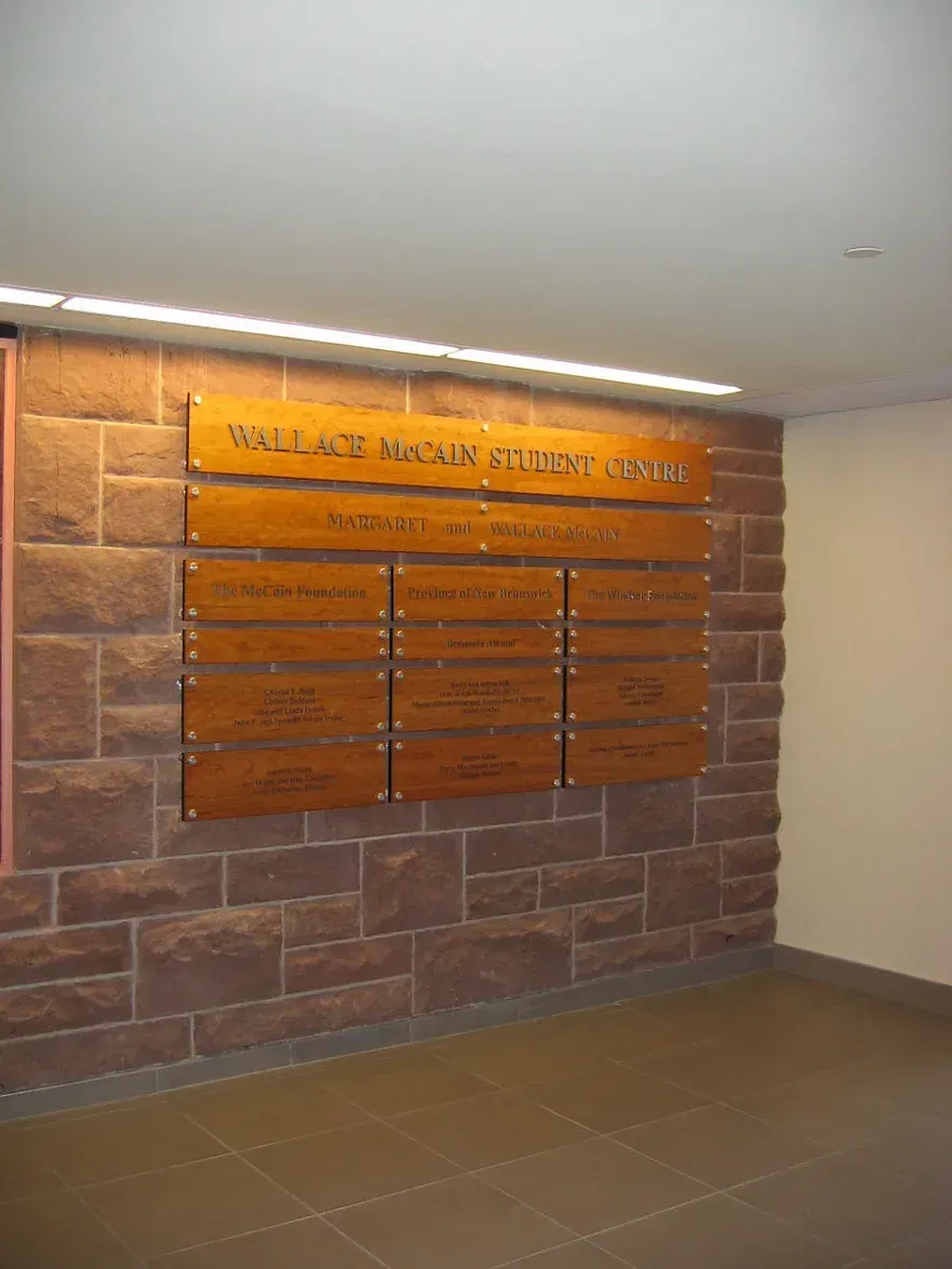 A brick wall with a wooden sign that says