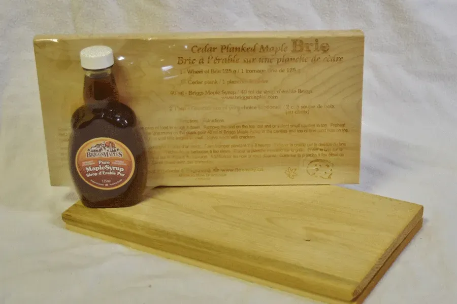 A bottle of maple syrup sits on a wooden cutting board