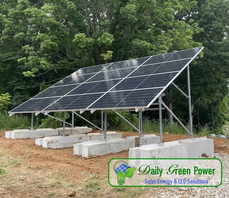 A row of solar panels are sitting on top of concrete blocks in a field.