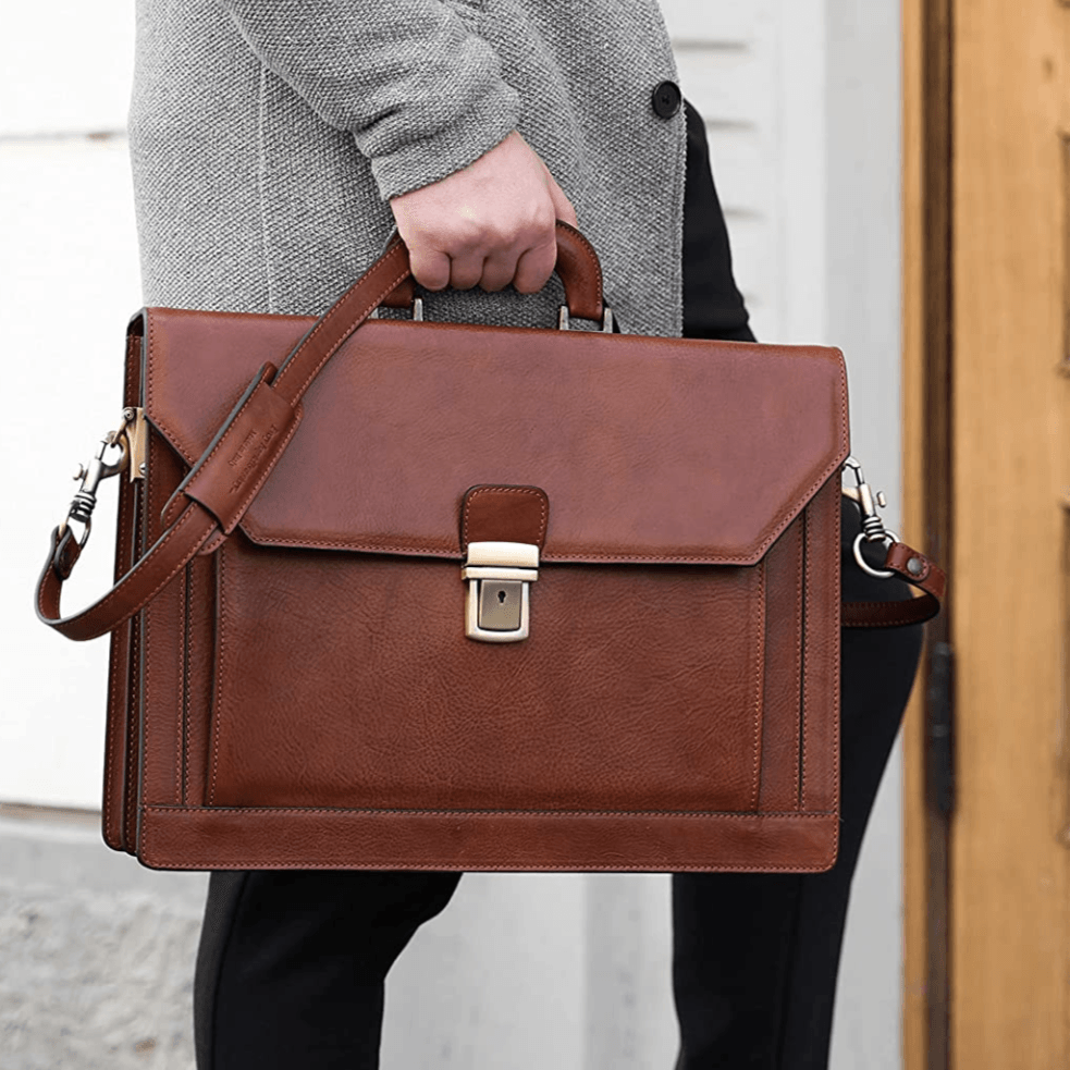 A man is carrying a brown leather briefcase with a shoulder strap