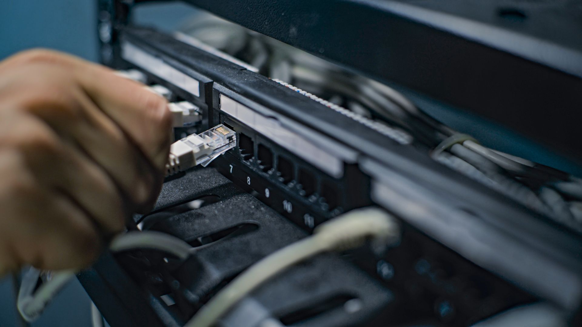 A person is plugging a cable into a server.