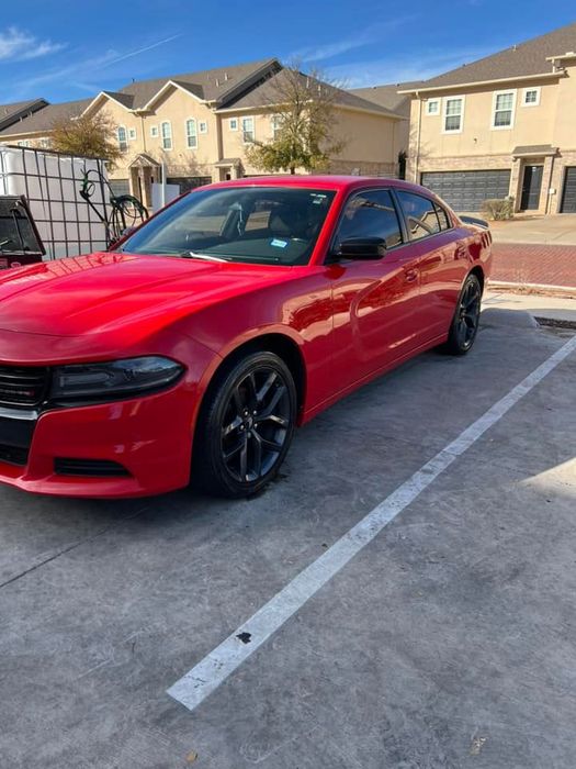 A red dodge charger is parked in a parking lot.