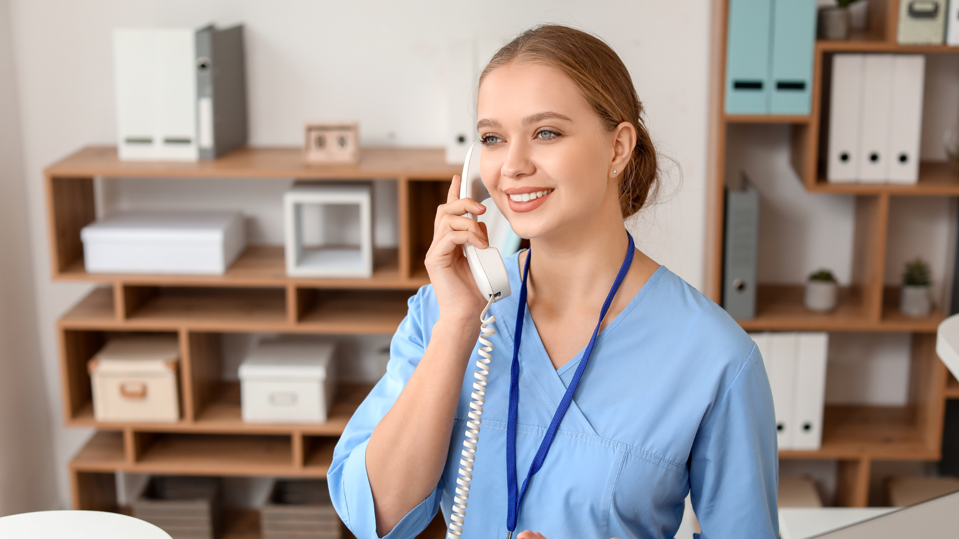 A nurse is talking on a telephone in an office.