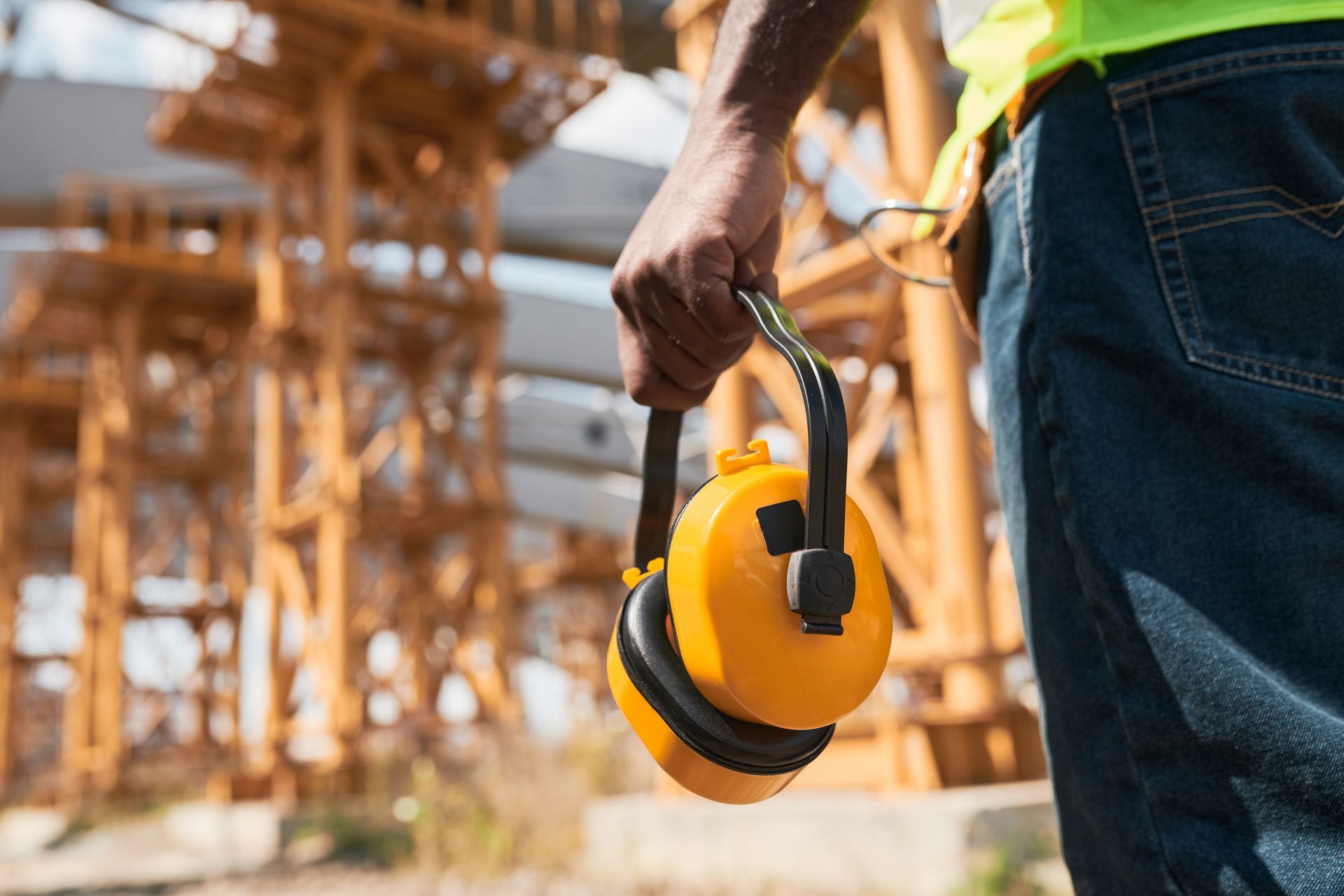 Ein Bauarbeiter trägt auf einer Baustelle Ohrenschützer und einen Schutzhelm.