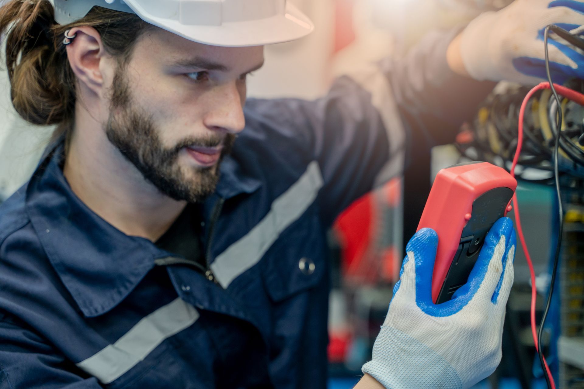 Ein Mann mit Schutzhelm hält ein Multimeter in der Hand.