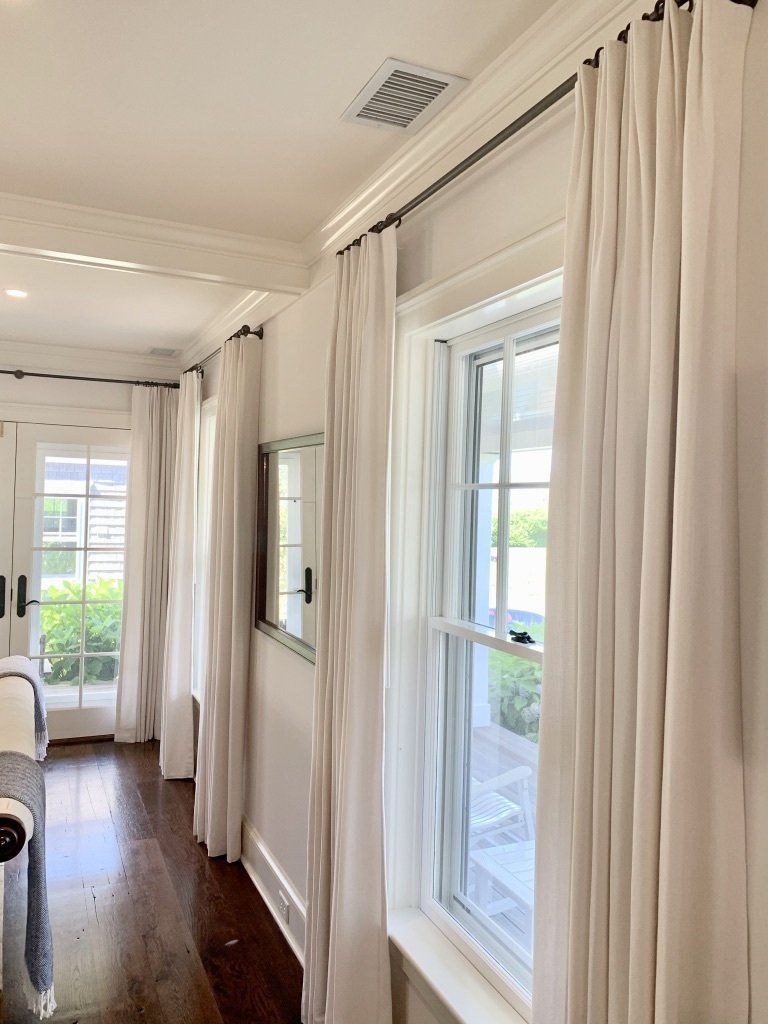 a bedroom with white curtains and a mirror on the wall Simply Windows.
