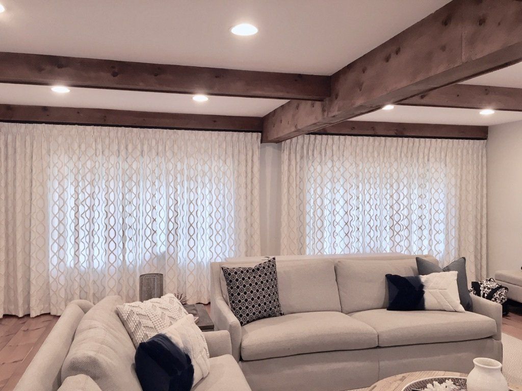 a living room with a couch , table , and drapery Simply Windows.