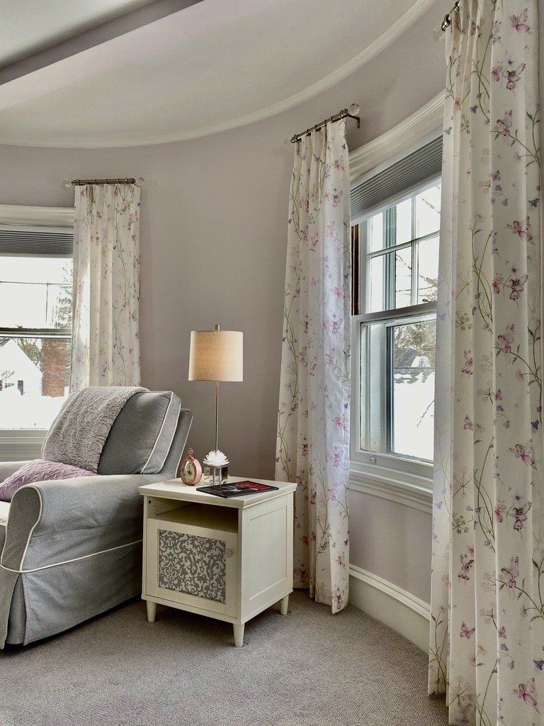 a living room with a chair , nightstand , lamp and window Simply Windows.