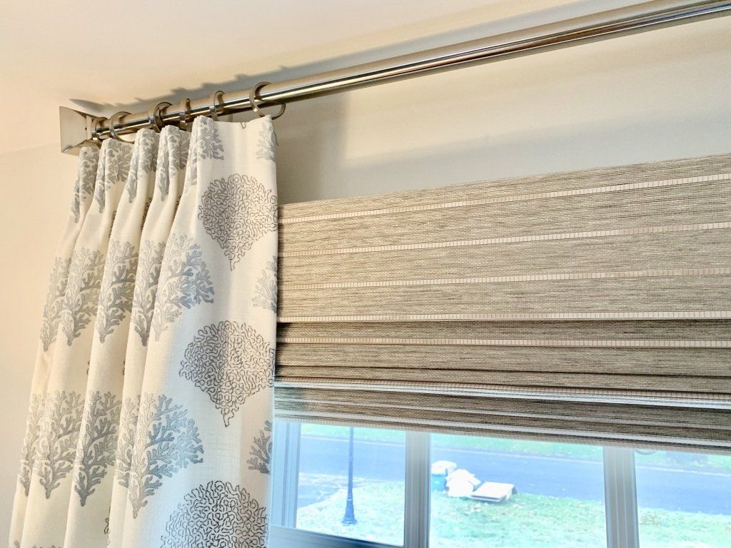 a close up of a window with curtains and roman shades Simply Windows.