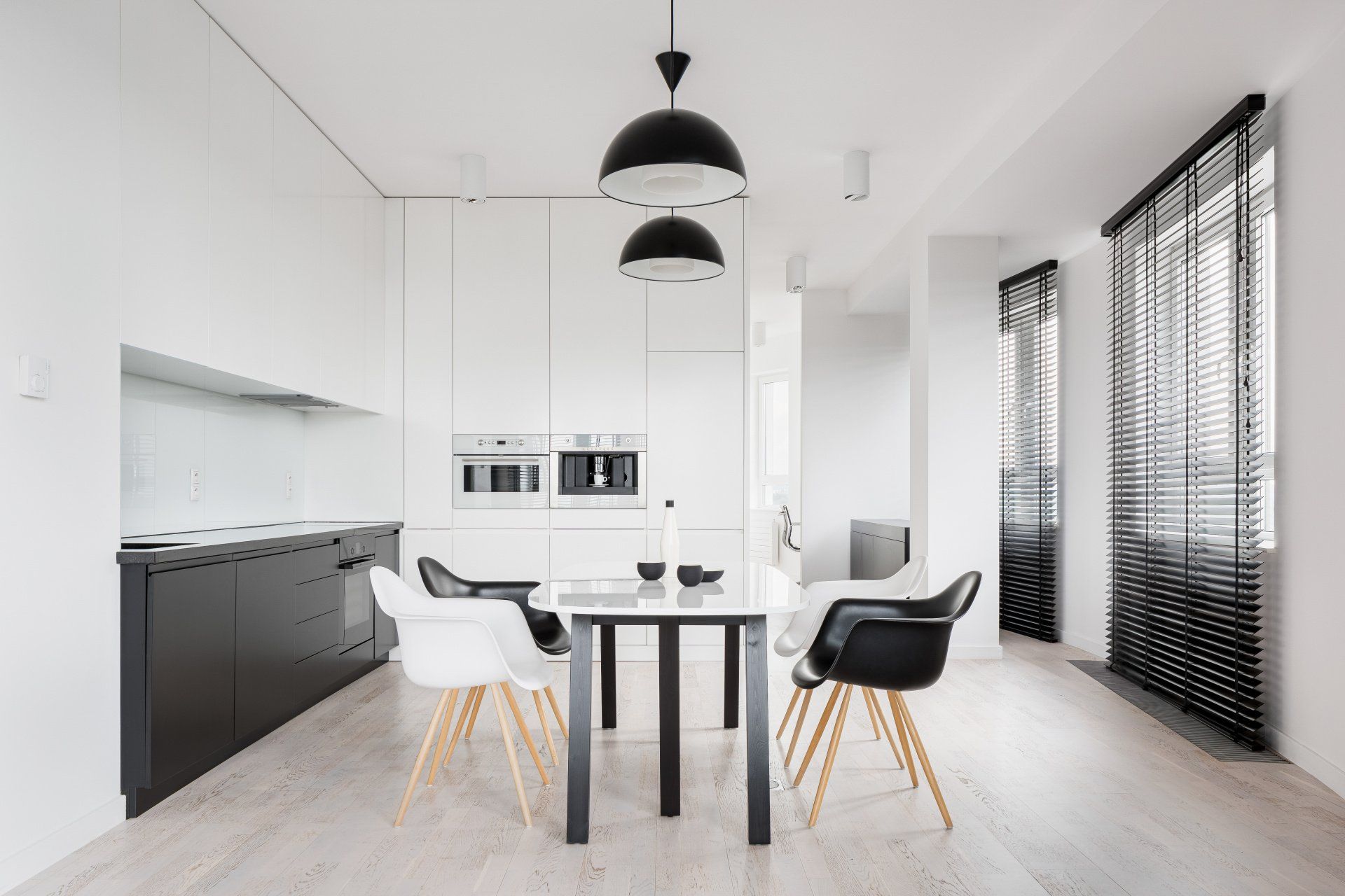 a black and white kitchen with a dining table and chairs and a window with blinds Simply Windows.
