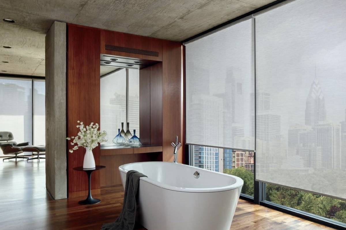 a bathroom with a bathtub and a large window with custom roller shades Simply Windows.
