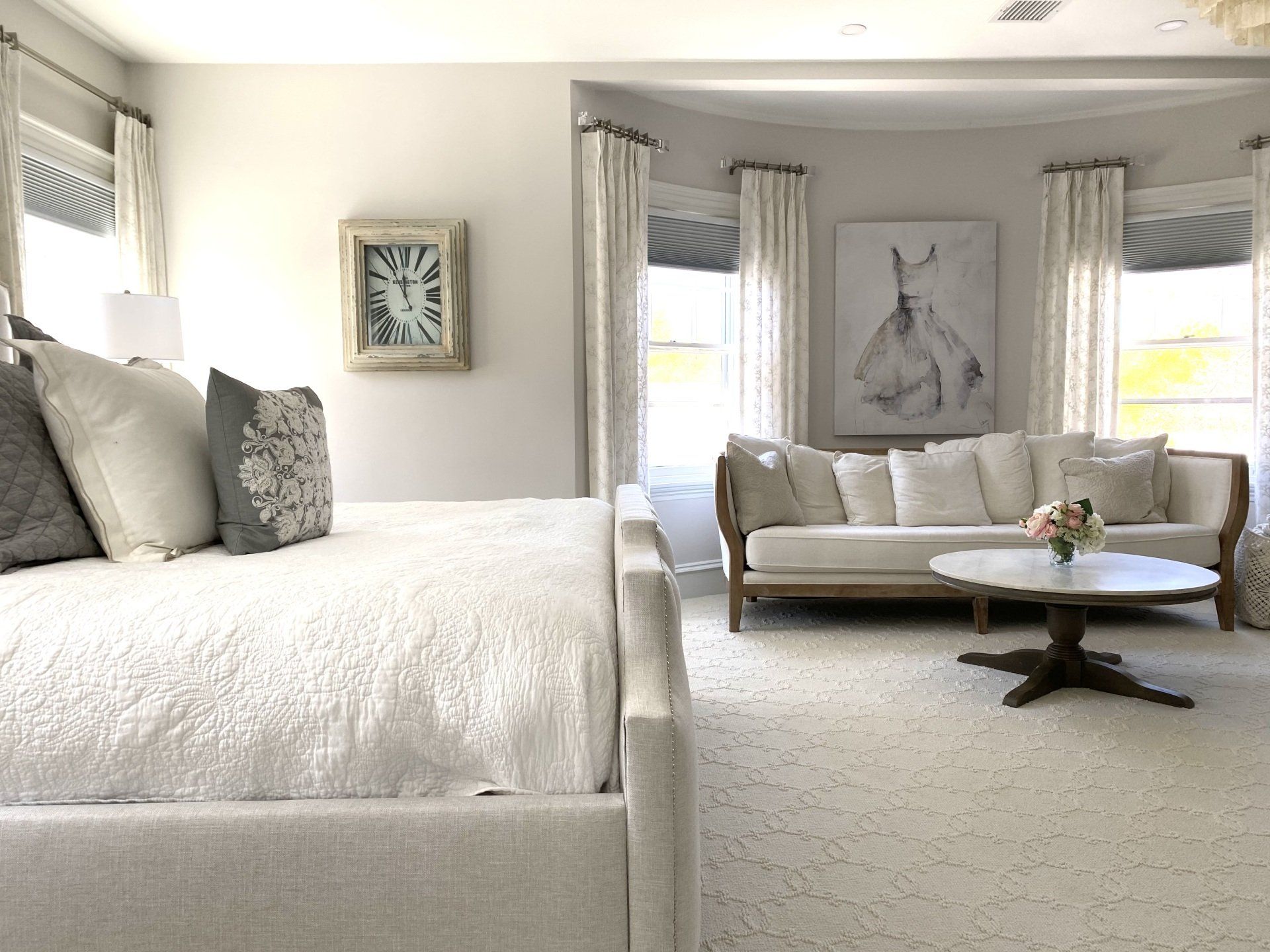 a bedroom with a bed , couch , coffee table and a clock on the wall Simply Windows.