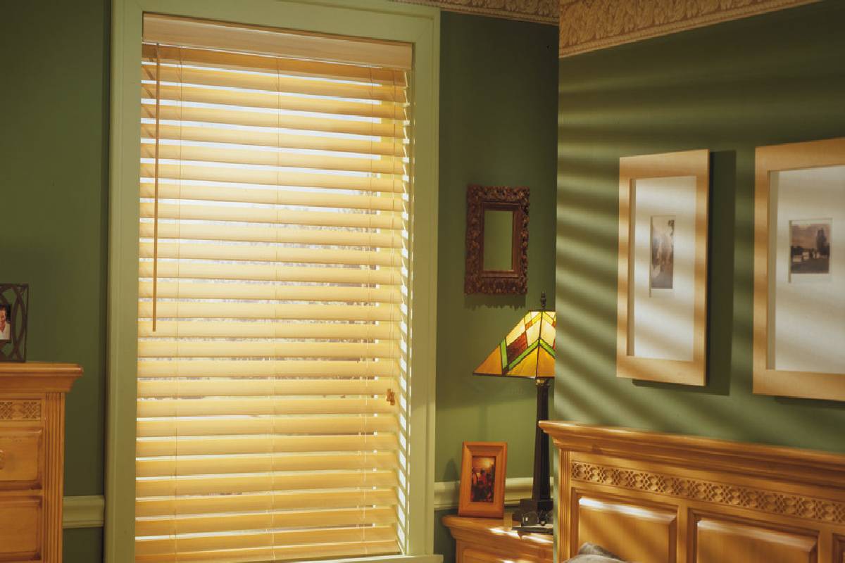 a bedroom with green walls and faux wooden blinds on the window Simply Windows