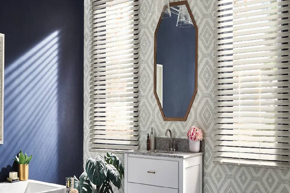 a bathroom with a sink , mirror , and faux wood window blinds Simply Windows.