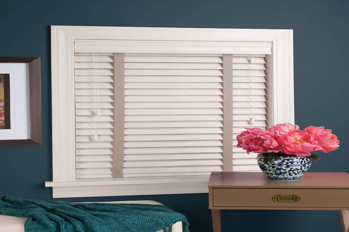 there is a vase of flowers on a table in front of a window with faux wood blinds Simply Windows.