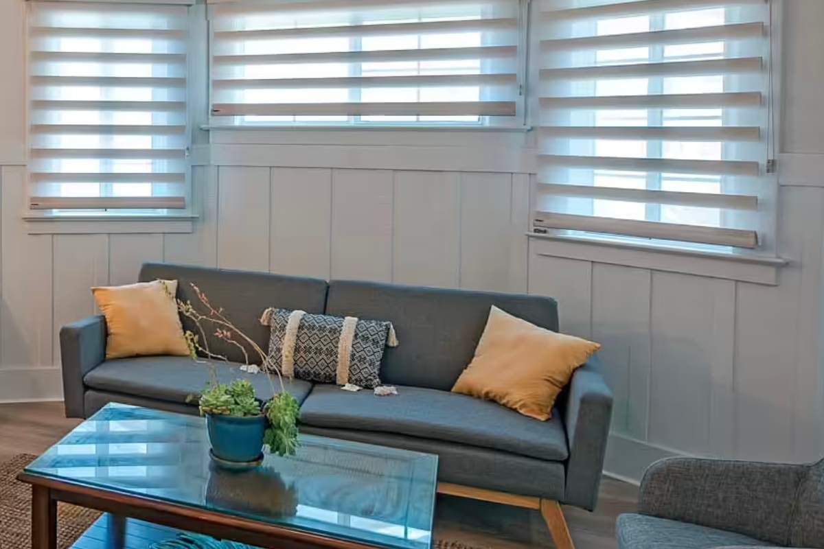 a living room with a couch , chair , and coffee table and sheer shadings on the windows Simply Windows.