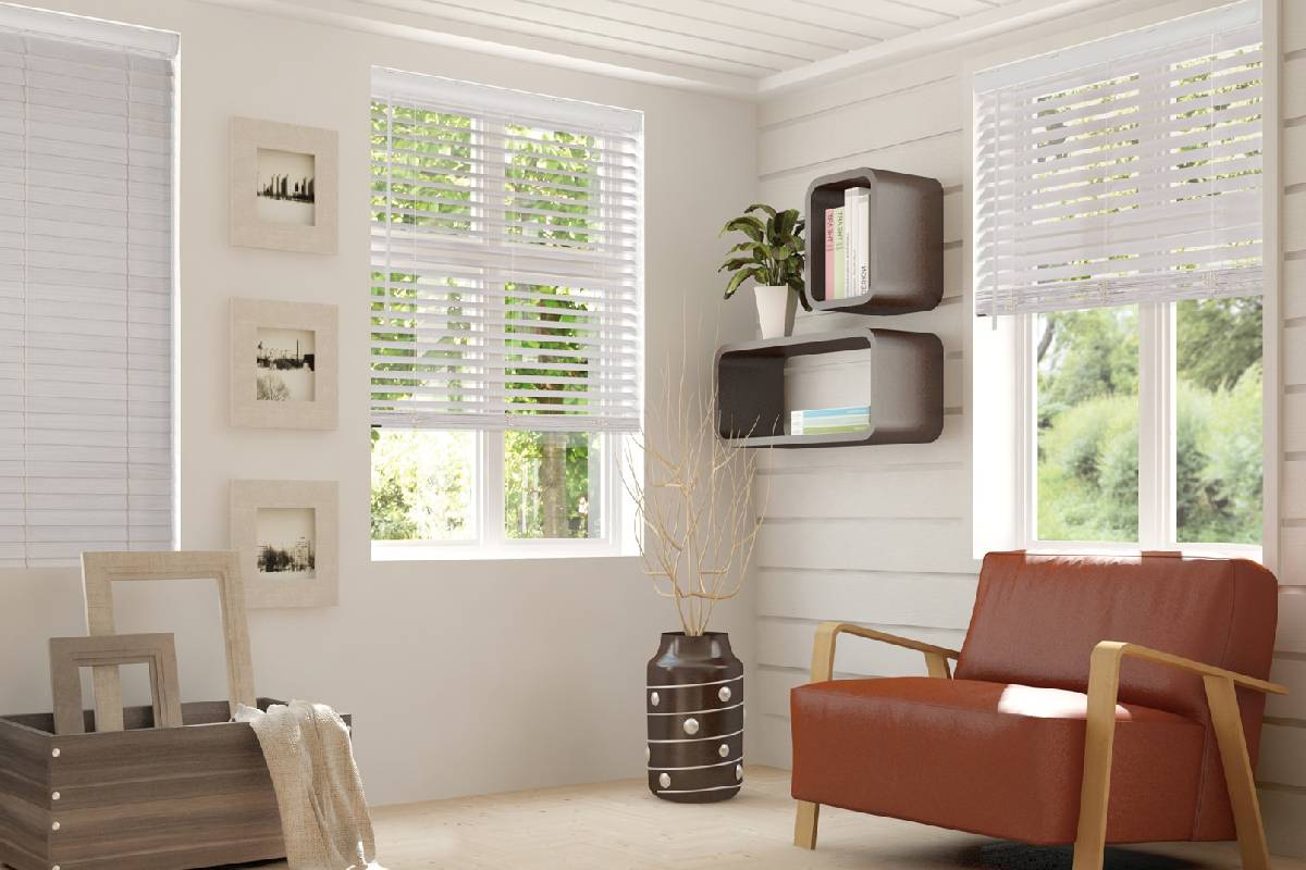 a living room with a couch , chair , shelves and windows with wood blinds Simply Windows.