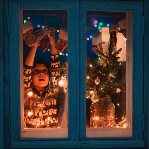 10 Tips for Christmas Window Decorations: A child puts up vintage Christmas decorations.