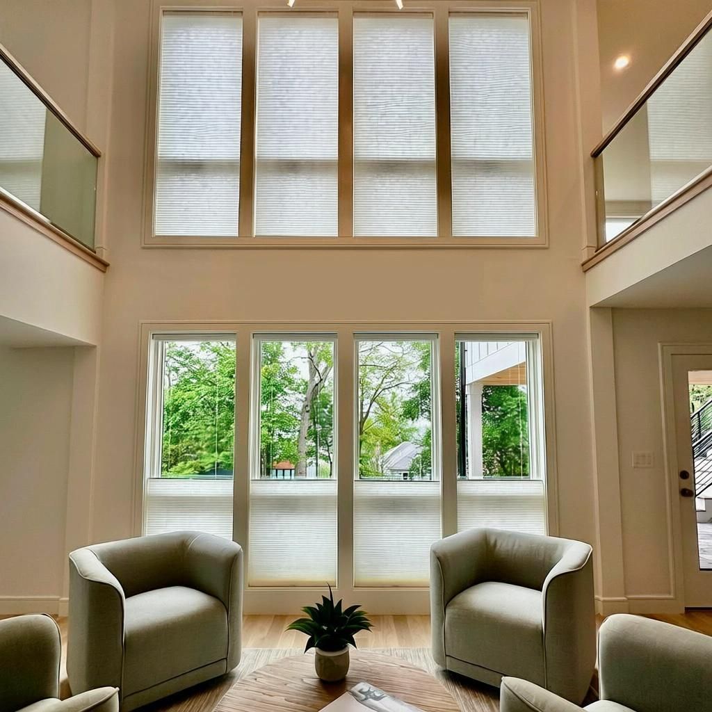 A light-filled living room with large windows, two armchairs, and a small round rug.