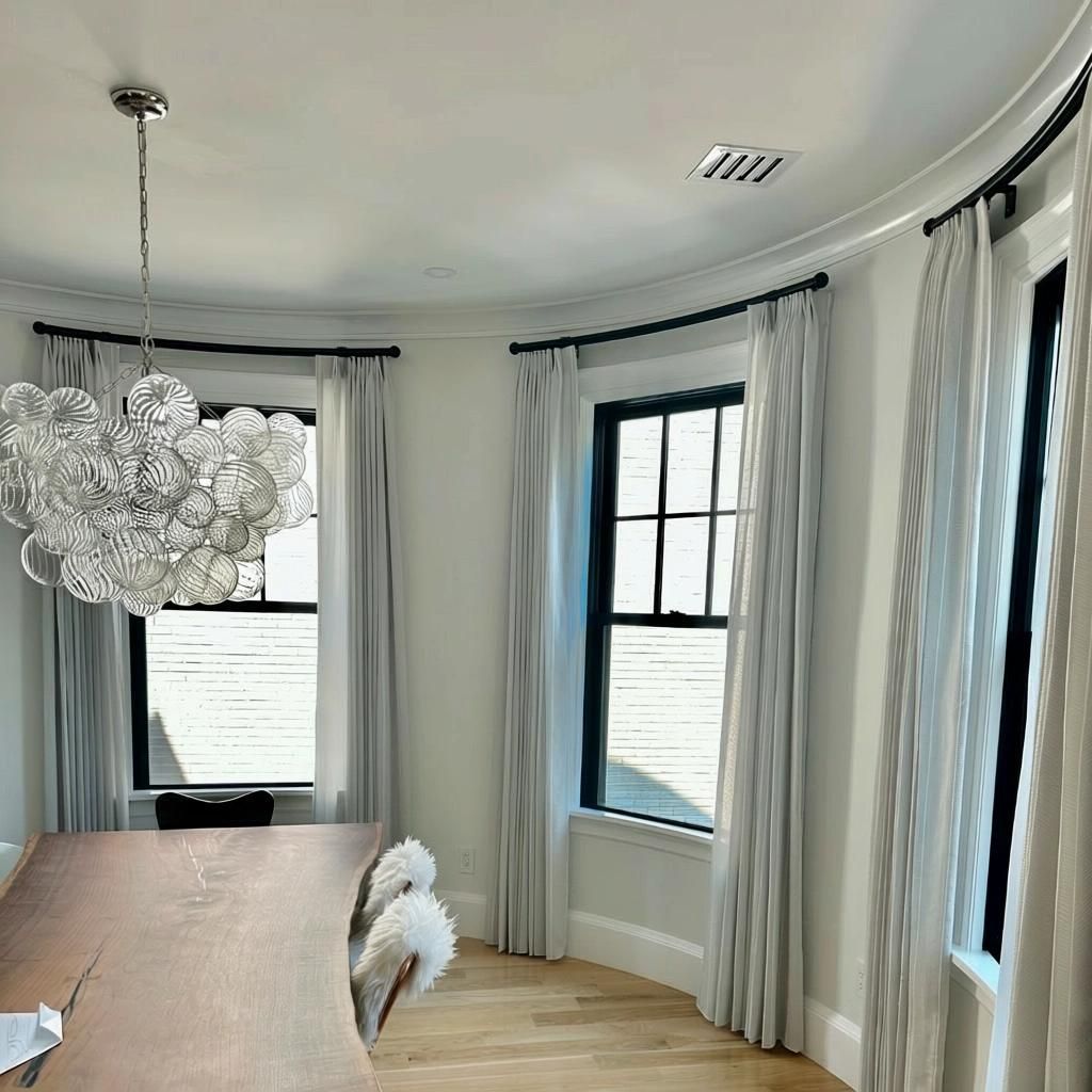 Dining room with large windows, light gray curtains, and a bubble-shaped chandelier.
