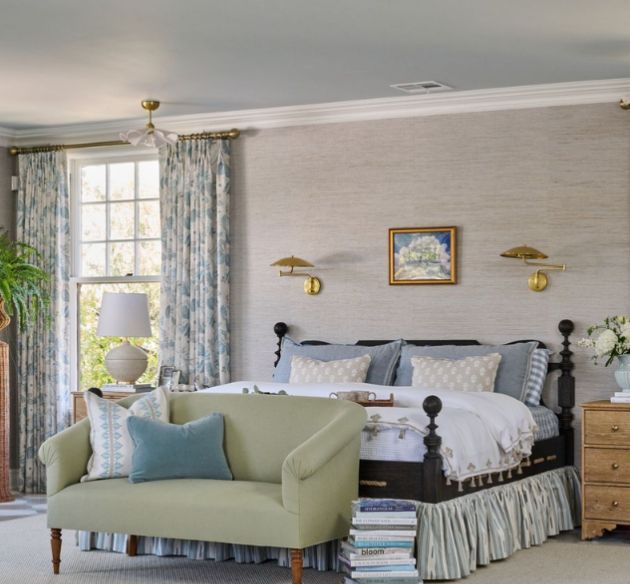 A bright bedroom with a bed and fabrics on the bed, drapes, and blankets. 