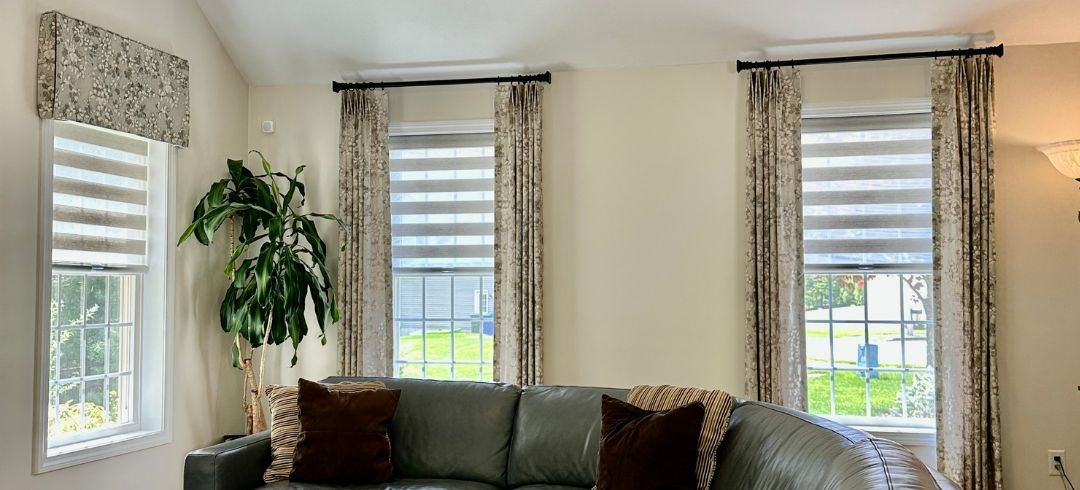 A living room has drapery, shades, and cornices to provide an inviting atmosphere - simply windows