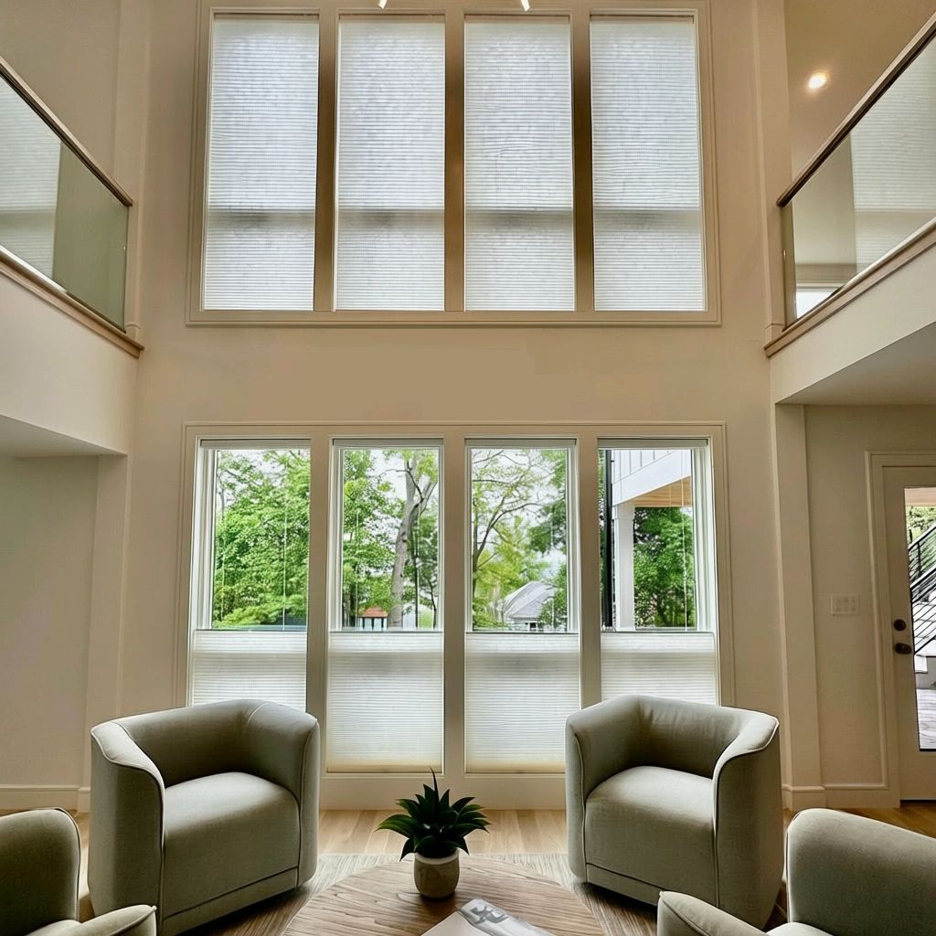 A room with a two-story ceiling has cellular shades on the high windows - simply windows