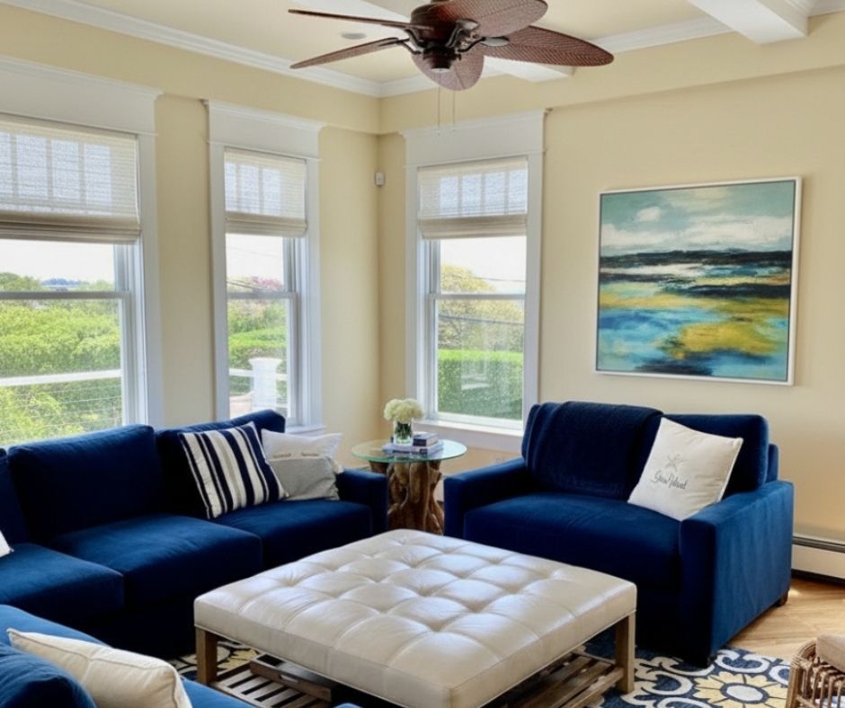 A comfortabe living room with blue sofas has woven wood roller shades.