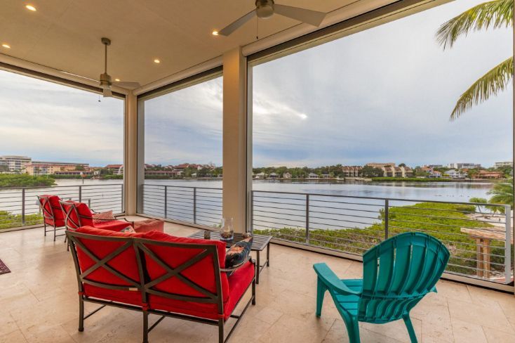 A patio with exterior patio shades, a view of a lake and a couch and chairs. Simply Windows