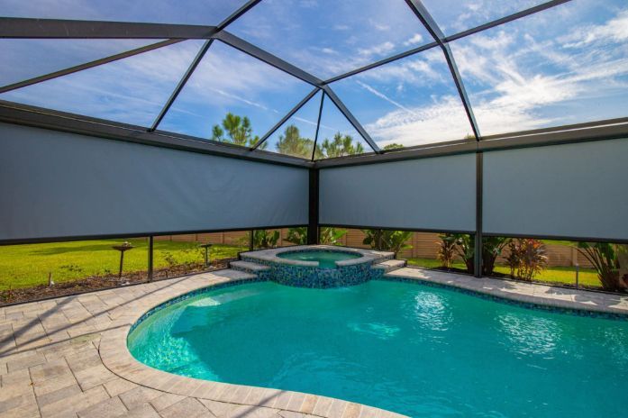 A large swimming pool with exterior patio shades surrounding it.