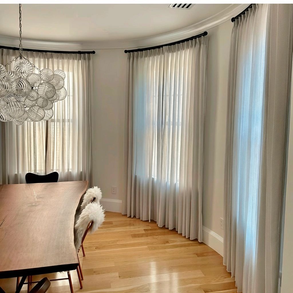 A round dining room with specialty curved windows has custom curved drapery hardware - simply windows
