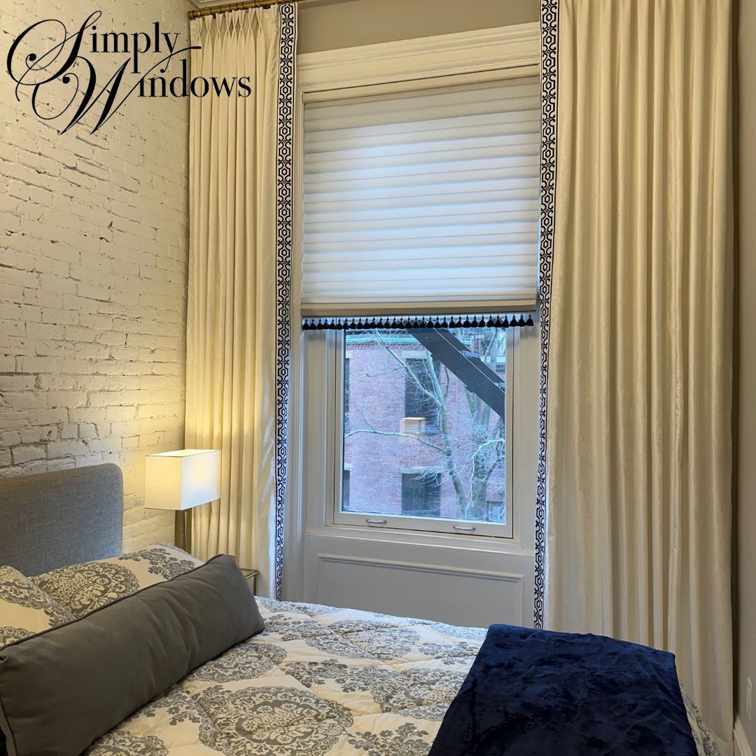 Cozy bedroom with white brick wall, window seat, cream curtains, and patterned bedding on a gray bed
