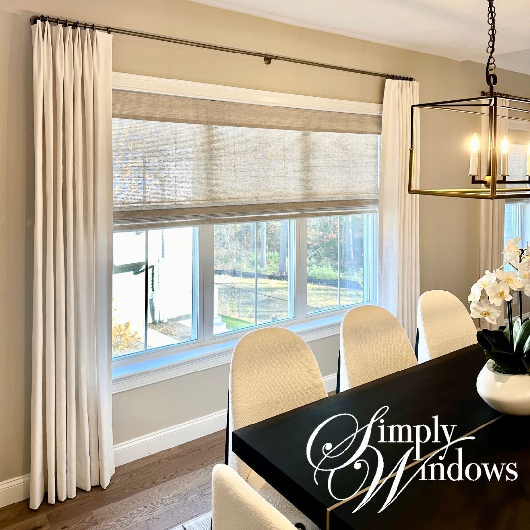 Bright dining room with cream drapery, woven shades, black table, and hanging light fixture