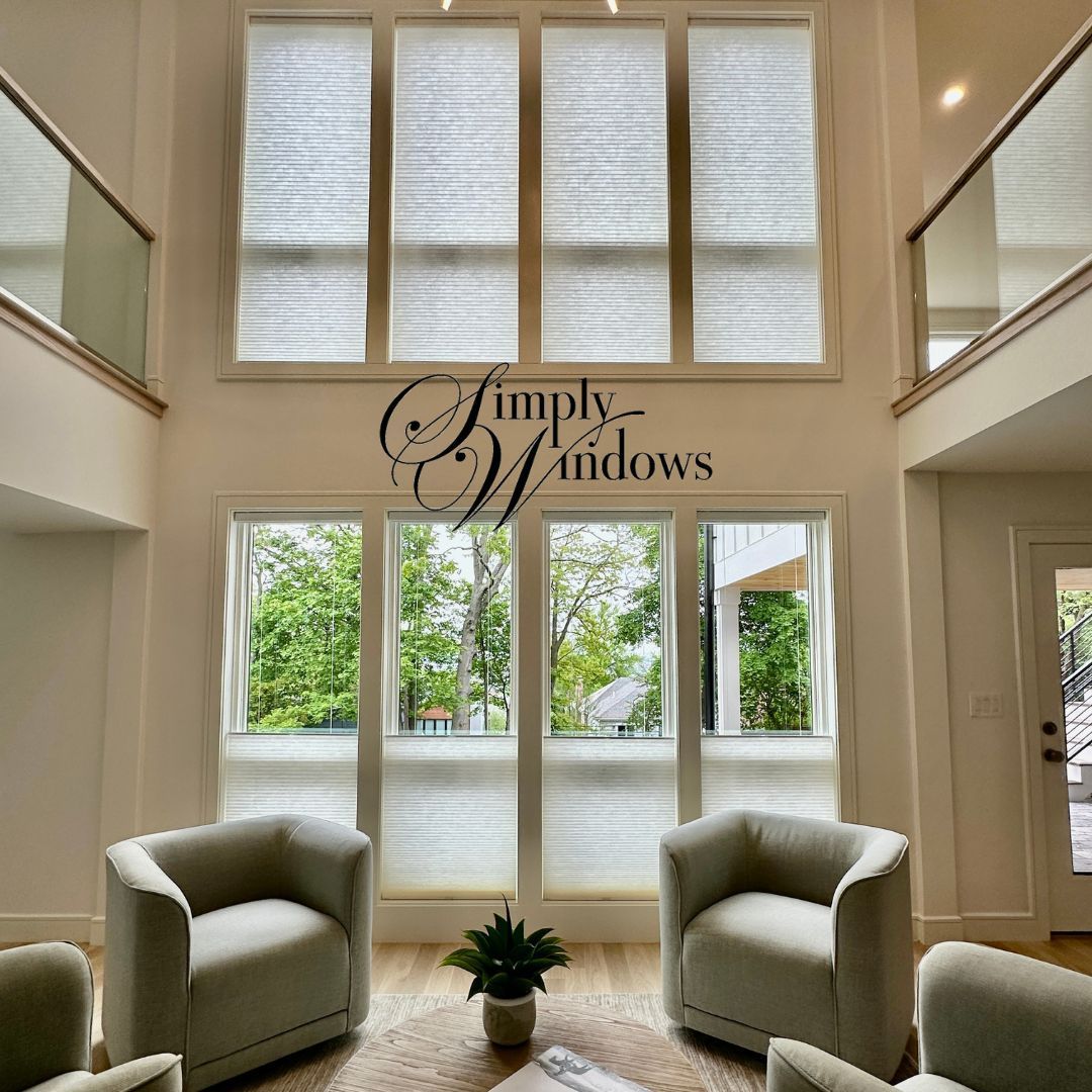 Living room with high windows, light-colored walls, and two armchairs facing the windows. The space has natural light.