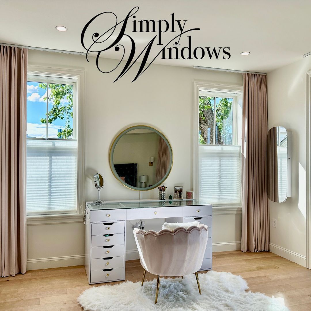 Bright vanity room with white desk, round mirror, blush chair, beige custom drapery, and soft natural light.