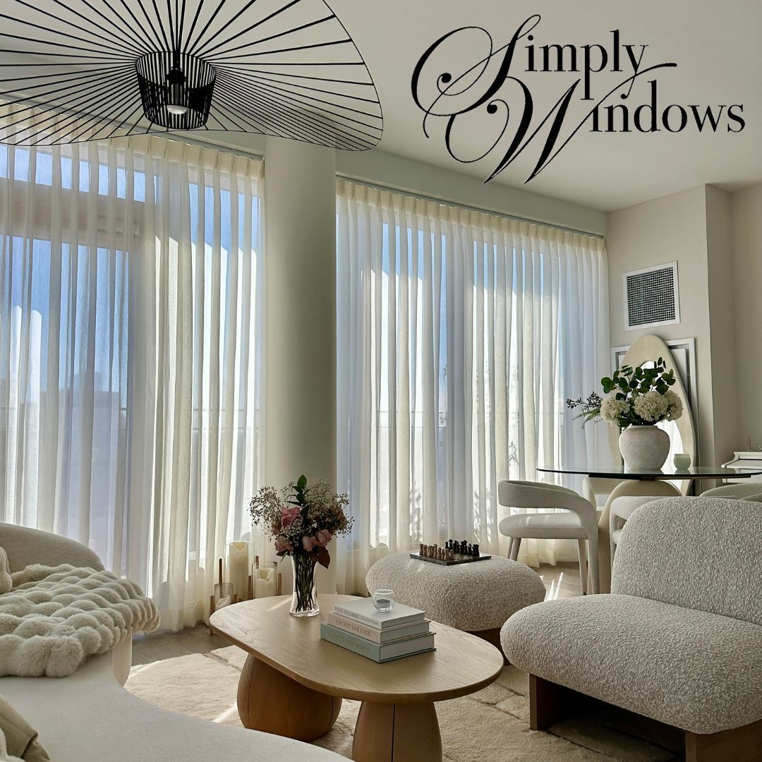 Living room with sheer white curtains, furniture in neutral tones, and a coffee table.